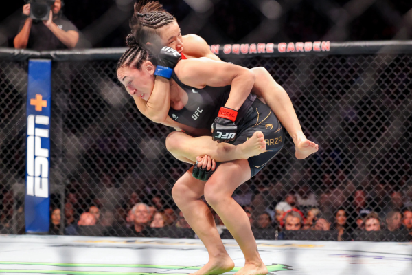 Twee vrouwelijke MMA-vechters in actie tijdens een UFC-gevecht, waarbij één vechter een rear-naked choke uitvoert op haar tegenstander.
