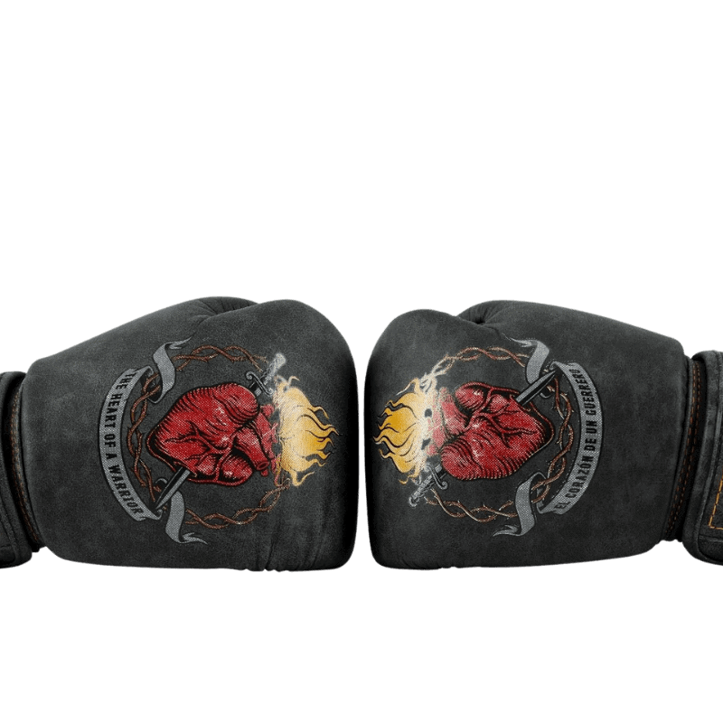 Zwarte bokshandschoenen met een rood hart en gele vlammen op de bovenkant, omgeven door een grijs lint met de tekst 'Heart of Champions' in gotische letters.