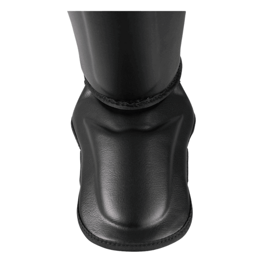 Een bovenaanzicht van een zwarte bokshelm met een beschermend kinstuk en klittenbandsluiting aan de achterkant, op een zwarte achtergrond.