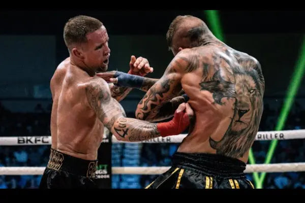 Een man geeft een vuiststoot in de buik van zijn tegenstander in de ring.