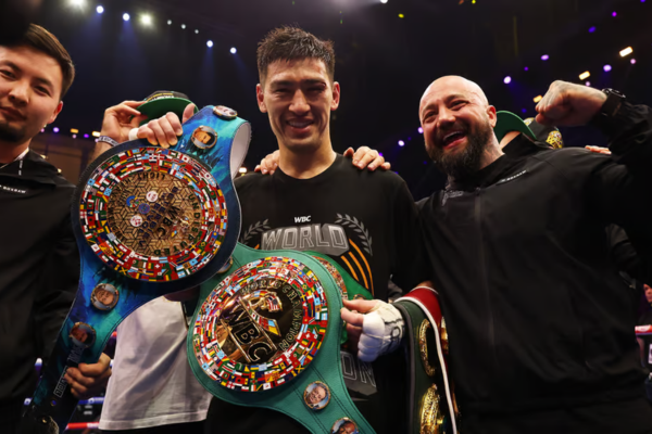 Professionele bokser viert zijn overwinning met meerdere WBC-kampioensgordels en teamleden in de ring na een succesvolle bokswedstrijd.