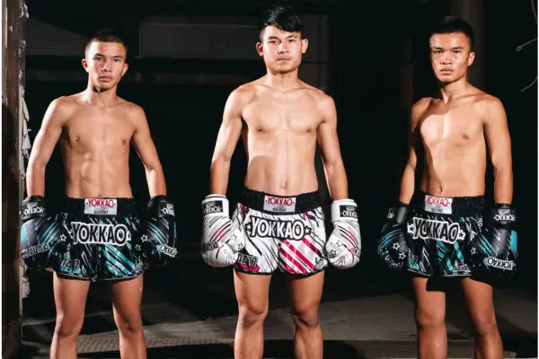 Drie Muay Thai-vechters dragen Yokkao shorts en bokshandschoenen – handgemaakt Thais design met Italiaanse stijl en topkwaliteit.