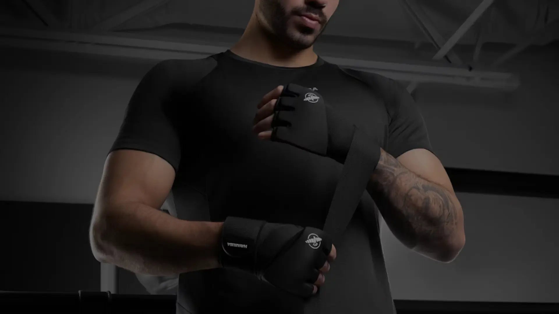 Close-up van een sporter die zwarte binnenhandschoenen en handwraps van Hayabusa om zijn handen wikkelt ter voorbereiding op een bokstraining.