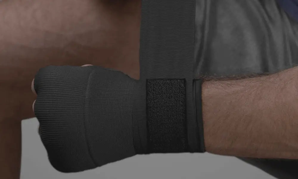 Close-up van een hand gewikkeld in een zwarte binnenhandschoen met een beschermend stuk rond de knokkels.