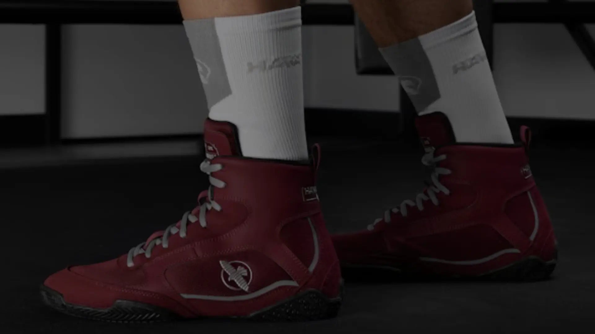 Close-up van rode Hayabusa boksschoenen gedragen tijdens een training, met gripvaste zolen en witte sportsokken zichtbaar.