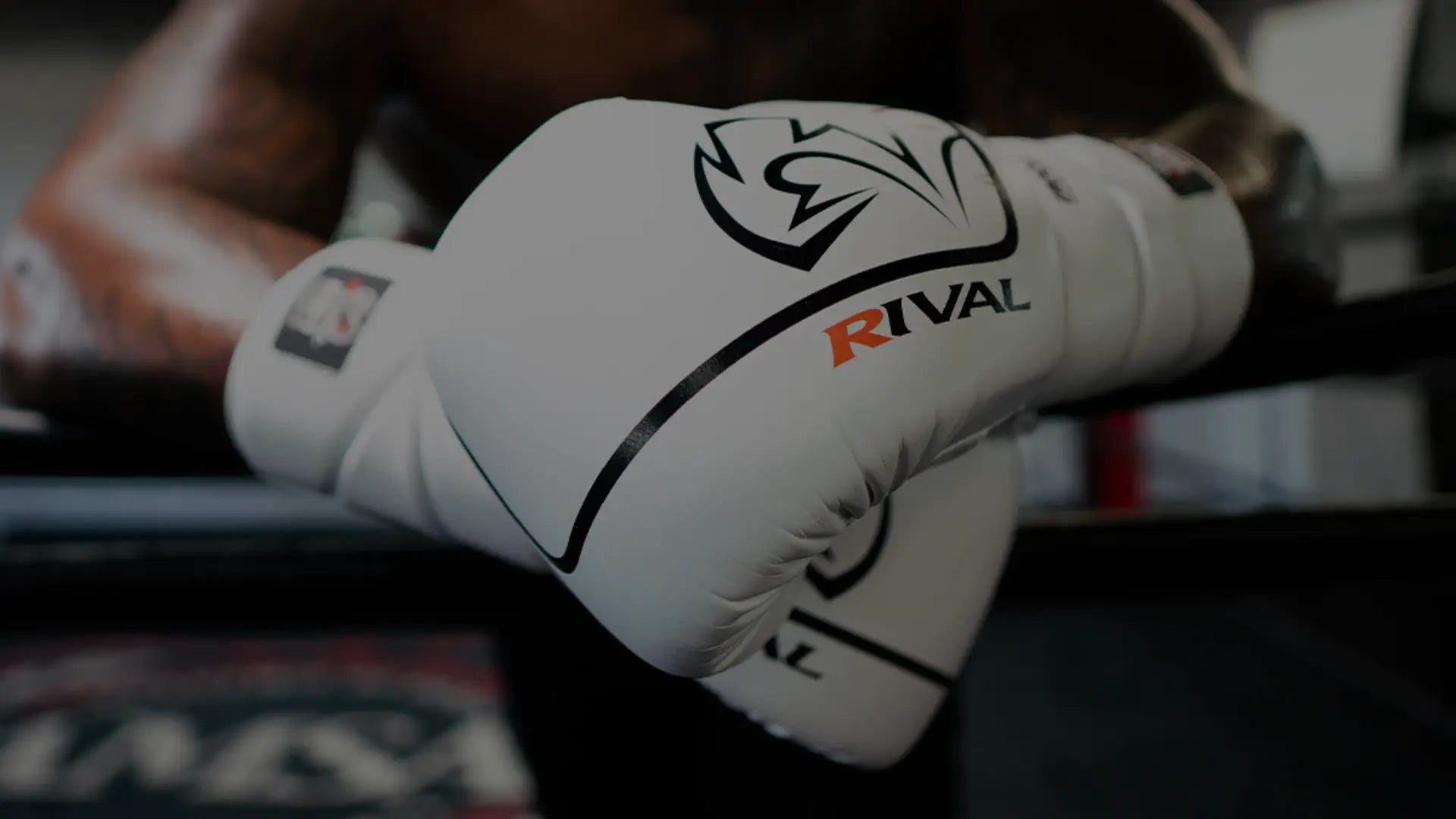 Een close-up van een bokshandschoen, gedragen door een atleet met een zichtbare gespierde torso en tatoeages.