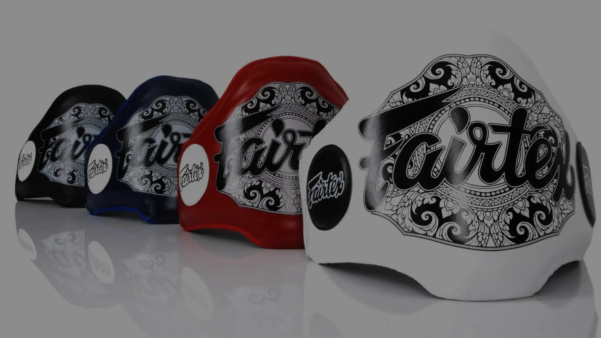 Vier Fairtex buikbeschermers in wit, rood, blauw en zwart, voorzien van gedetailleerde patronen en uitgelicht voor productpresentatie.