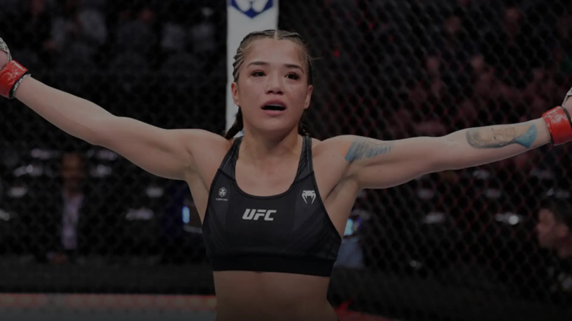 Een vrolijke vrouwelijke vechtsporter viert haar overwinning in de ring met een opgeheven vuist; ze draagt kleurrijke vechtsportkledij en handschoenen, met zichtbare tekenen van een recent gevecht op haar gezicht.