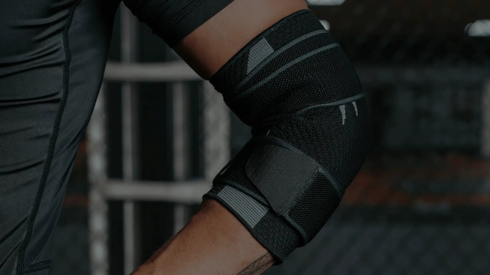 Close-up van een sporter die een zwarte, strak aansluitende elleboogbeschermer draagt voor ondersteuning en bescherming tijdens intensieve training.