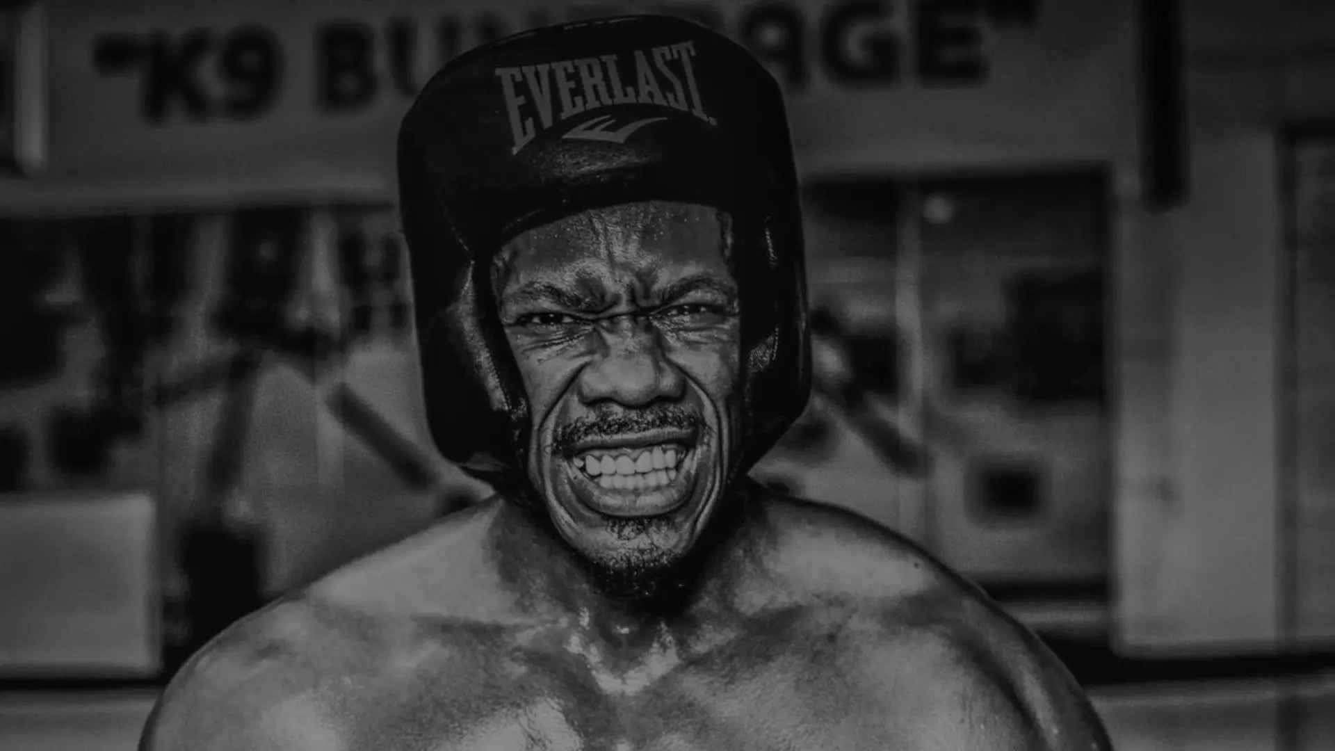 Een gespierde bokser draagt een hoofdbeschermer en maakt een intense, vastberaden gezichtsuitdrukking.