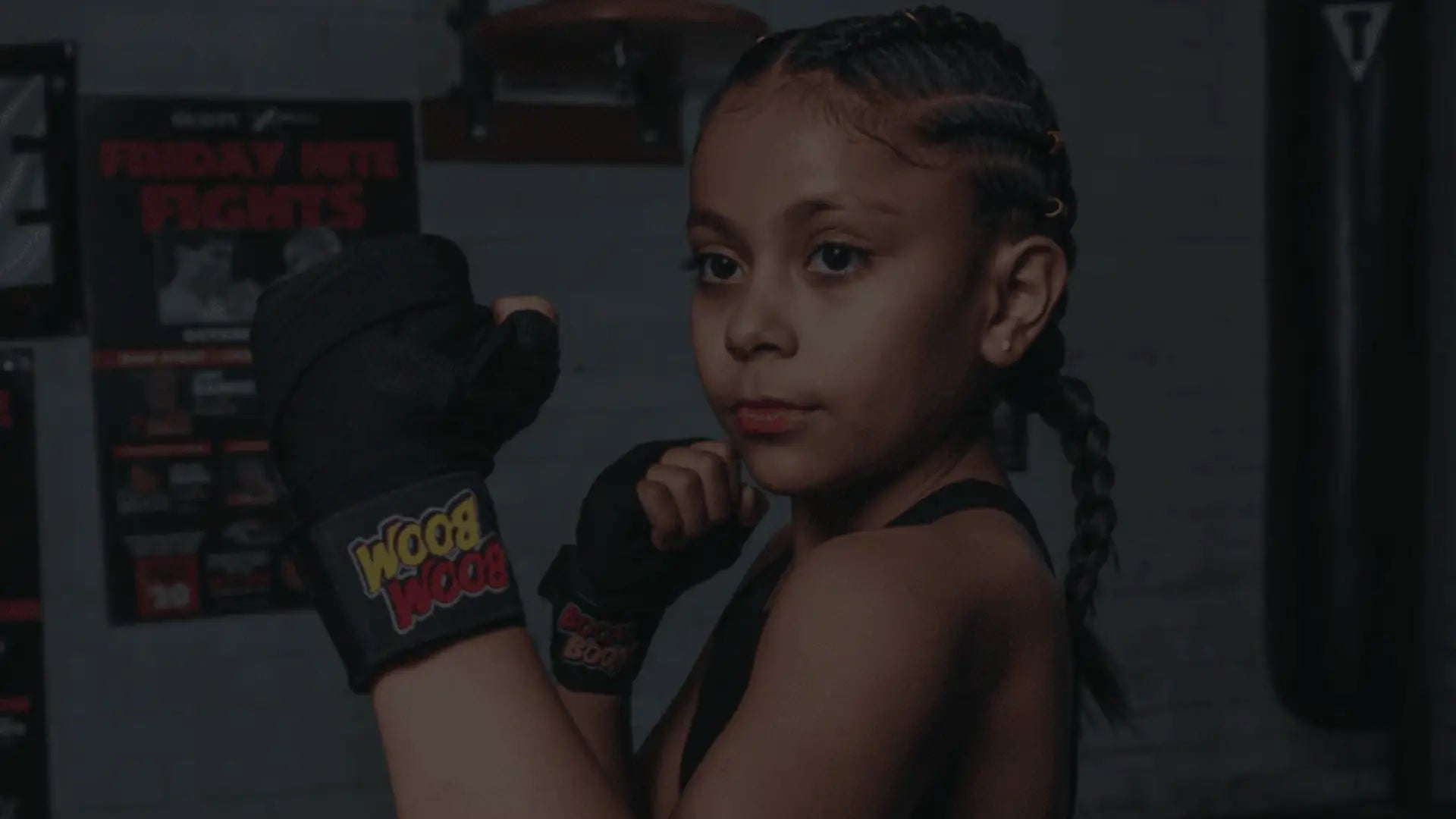 Een jong meisje in een gevechtshouding met bokshandschoenen aan, klaar om te sparren.