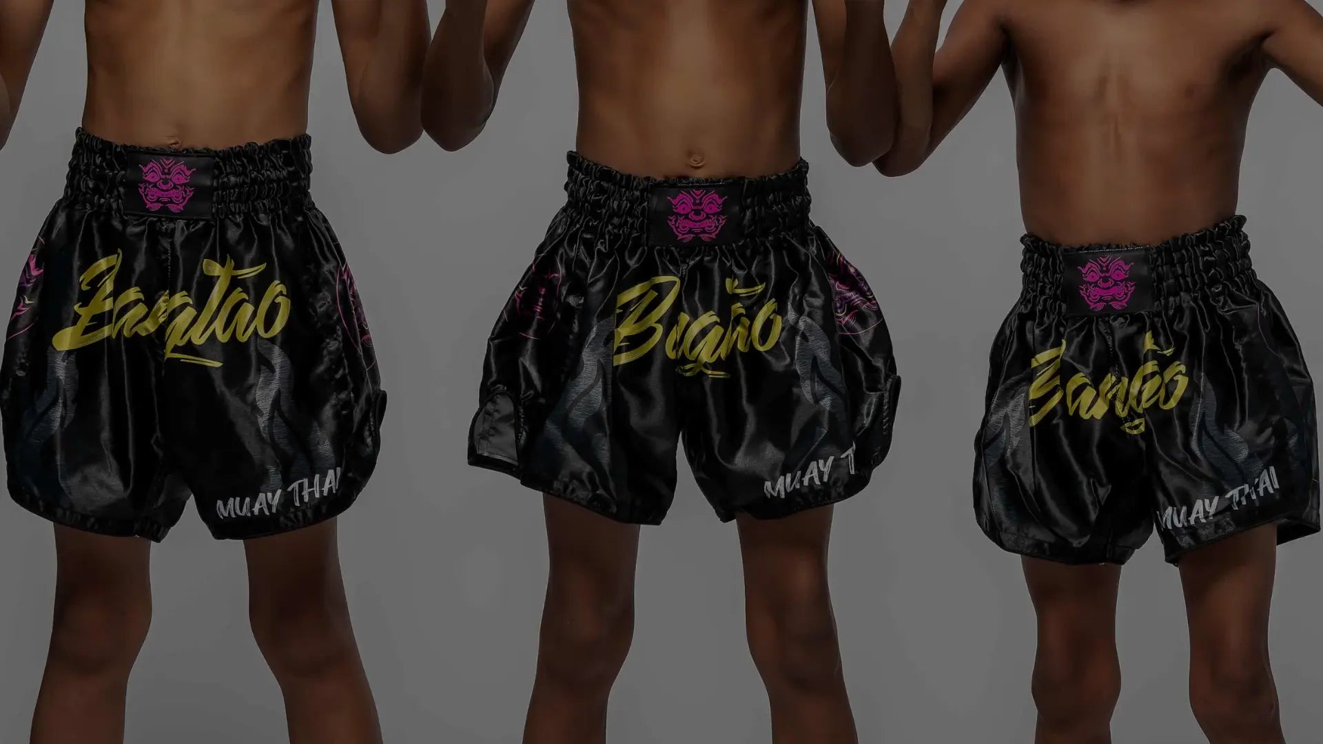 Drie kinderen in vechtsportuitrusting, twee met bokshandschoenen en één met scheenbeschermers.