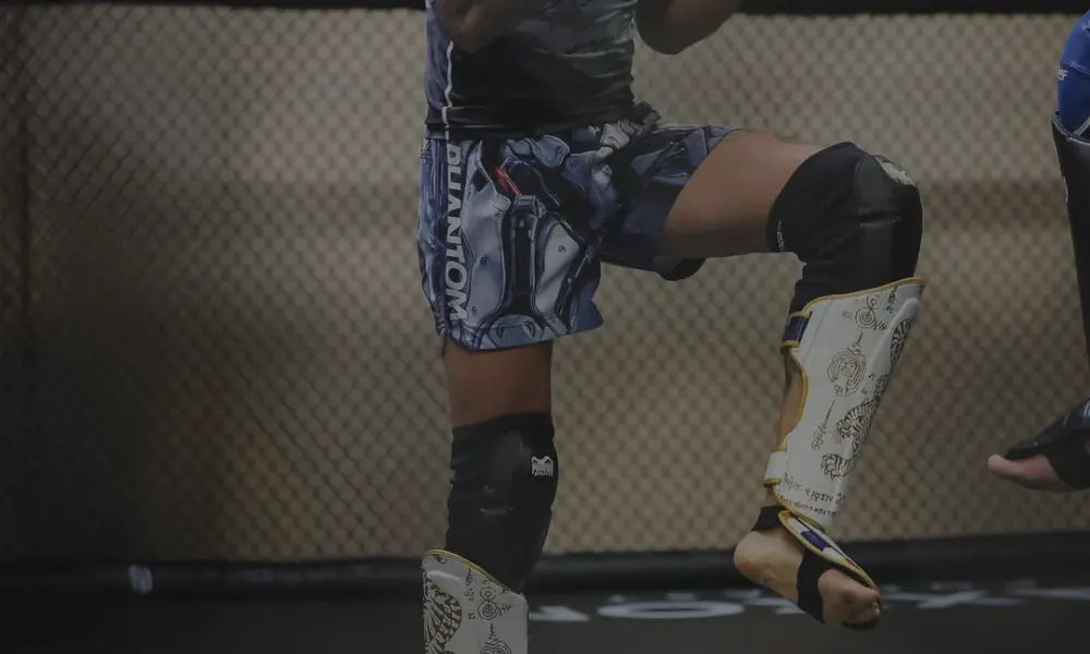 Close-up van een hand die wordt ingepakt met rode bokshandschoenen bandages door een trainer, in een gymomgeving.