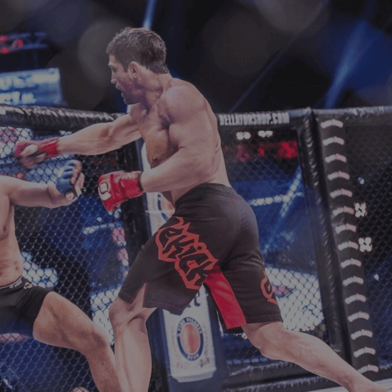Een gespierde MMA-vechter in actie binnen een octagon, gekleed in zwarte shorts met het Fairtex-logo, werpt een krachtige stoot naar zijn tegenstander tijdens een gevecht.