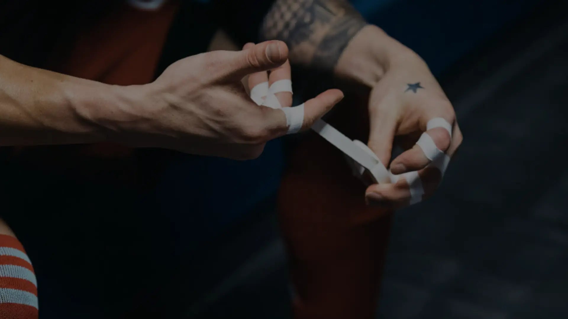 Close-up van een atleet die zijn vingers intapet ter voorbereiding op een intensieve training of wedstrijd, met zichtbaar gespannen handen en sportkleding.