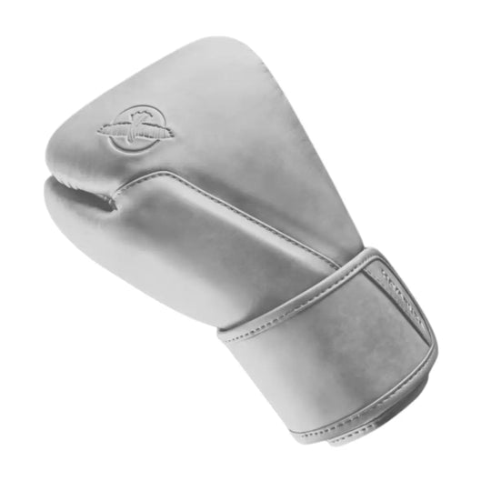 Zijaanzicht van een witte bokshandschoen met een strakke, matte afwerking en moderne uitstraling. Het subtiele reliëflogo in dezelfde kleur versterkt het minimalistische karakter. De brede klittenbandsluiting en nauwkeurig afgewerkte stiknaden zorgen voor optimale polsstabiliteit en een duurzame, hoogwaardige constructie.