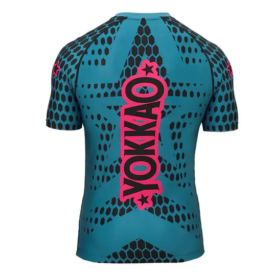 Achteraanzicht van het Yokkao compression shirt Stargame in de kleur Ottanium. Het turquoise shirt heeft een zwart honingraatpatroon met een groot roze Yokkao-logo verticaal over de rug. De nauwsluitende pasvorm en korte mouwen bieden optimale ondersteuning en bewegingsvrijheid tijdens intensieve trainingen.