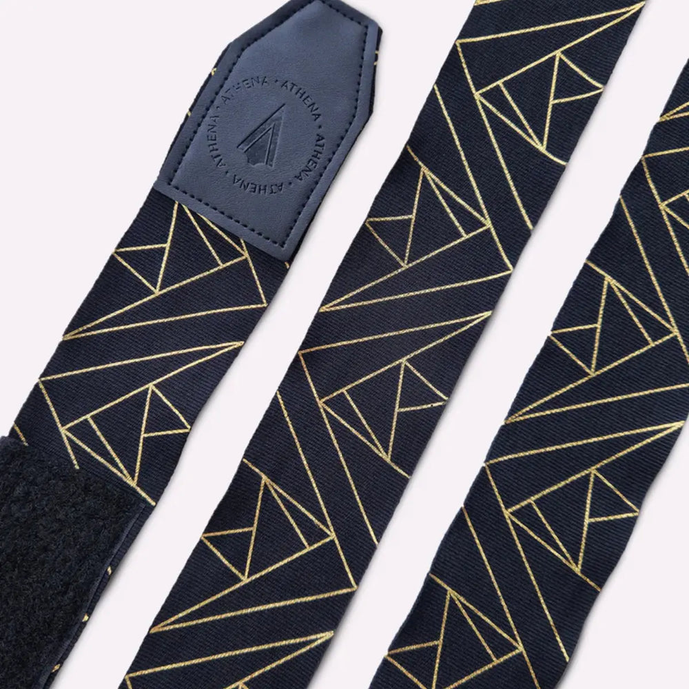 Detailfoto van de Athena Fightwear handwraps plat neergelegd met zichtbare gouden geometrische lijnen. De uiteinden tonen het leren label met het Athena-logo voor een luxe afwerking. De structuur van de bandage laat een duurzame, elastische kwaliteit zien. Ontworpen voor comfort en langdurig gebruik.