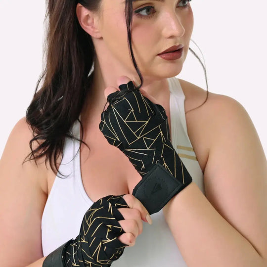 Model draagt de zwarte Athena Fightwear handwraps met goud geometrisch patroon. De wraps zitten strak om de handen gewikkeld voor optimale ondersteuning tijdens bokstraining. De close-up toont het elegante ontwerp dat past bij de vrouwelijke pasvorm. Perfect voor dagelijks gebruik tijdens intensieve trainingssessies.