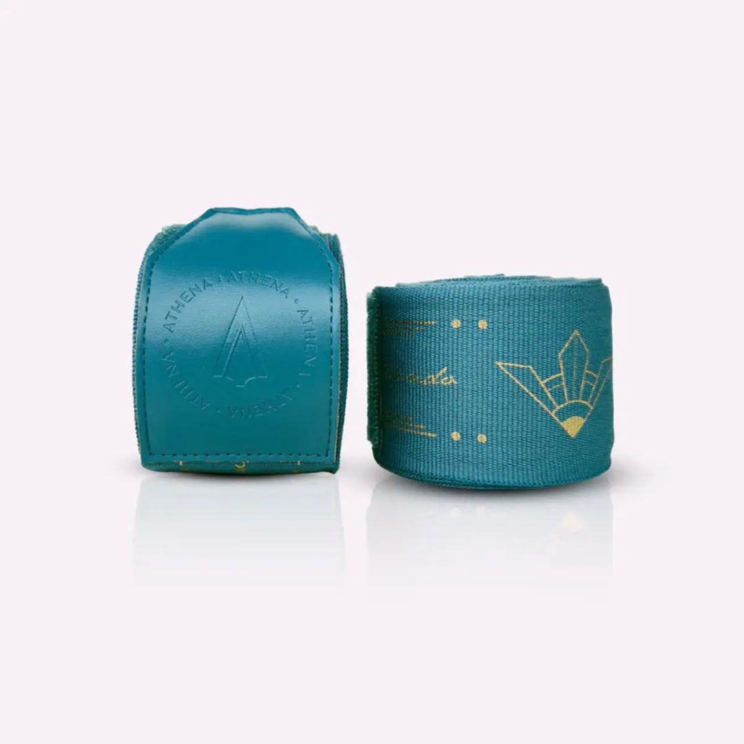 Athena Fightwear Diana Teal bandages opgerold en uitgespreid, turquoise met goud detailprint voor extra pols- en handsupport.