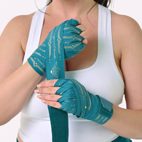 Vrouw wikkelt Athena Fightwear Diana Teal bandages om haar handen voor kickboksen, met duidelijke pasvorm en stretchweefsel.