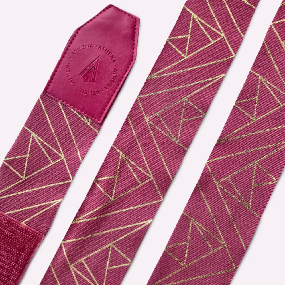 Detailfoto van de Eris Berry handwraps met goudkleurige geometrische patronen. Het leren uiteinde met het Athena-logo valt duidelijk op. De bandages liggen plat zodat het ontwerp goed zichtbaar is.