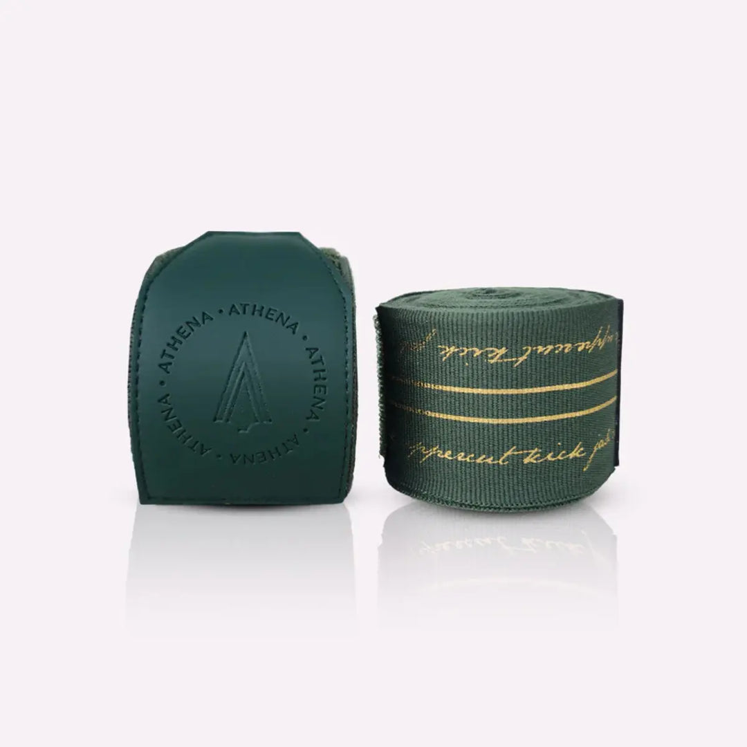 Athena Fightwear Nerio Hunter Green bandages opgerold en uitgespreid, donkergroen met goud accenten voor kickboksen en boksen.