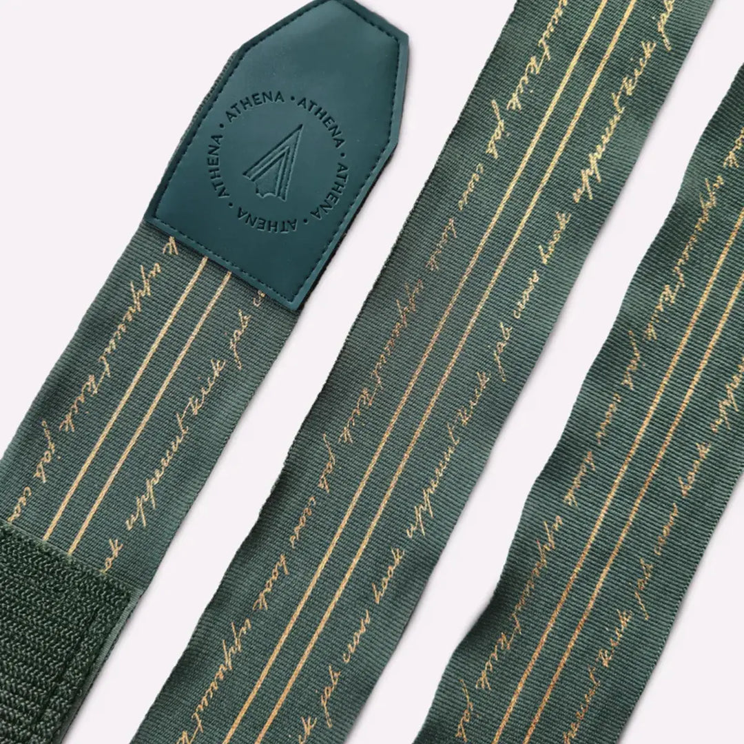 Uitgerolde Athena Fightwear Nerio Hunter Green bandages met goudkleurige lijnen en tekst voor een stijlvolle sportieve look.