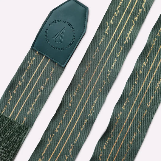 Uitgerolde Athena Fightwear Nerio Hunter Green bandages met goudkleurige lijnen en tekst voor een stijlvolle sportieve look.