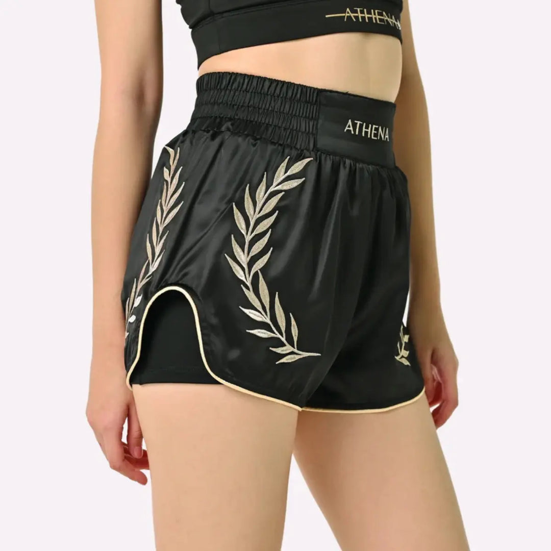 Athena Fightwear Thaiboks Broekje Zwart Goud gedragen door model met gouden lauwerdetails aan de zijkant.
