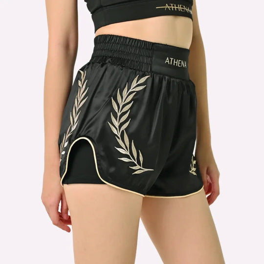 Athena Fightwear Thaiboks Broekje Zwart Goud gedragen door model met gouden lauwerdetails aan de zijkant.