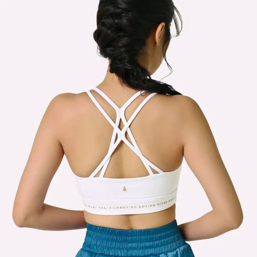 De afbeelding toont de achterkant van de Thessalia sport-BH van Athena Fightwear, met elegante, meerdere gekruiste bandjes en een stevige elastische band onder de borst, gedragen door een vrouwelijke atleet.