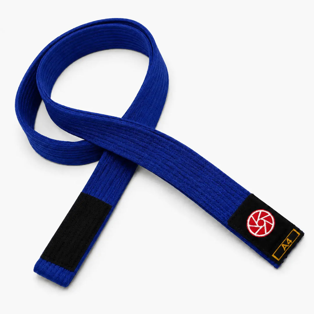 Blauwe BJJ band met zwarte uiteinden en Martial Arts Center logo op het label. De stevige geweven structuur en duidelijke A4-maataanduiding maken de band geschikt voor BJJ-trainingen en graduaties.
