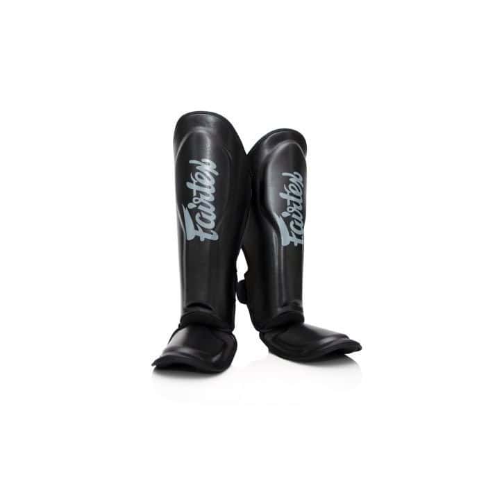 Zwarte Fairtex scheenbeschermers recht van voren gefotografeerd, met zilvergrijze Fairtex-logo’s zichtbaar op beide schenen. Ideaal voor kickboksers die op zoek zijn naar duurzame bescherming en een stijlvolle look.