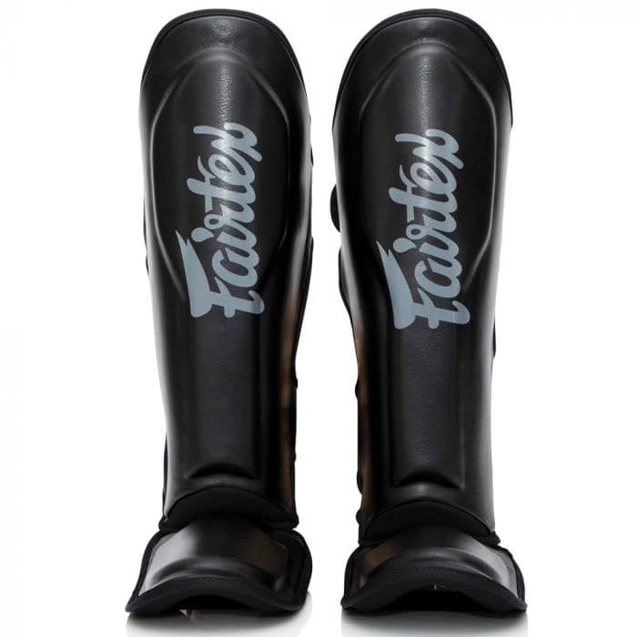 Vooraanzicht van zwarte Booster FXB scheenbeschermers met lichtgrijs Fairtex-logo, geschikt voor kickboksers en intensieve training.