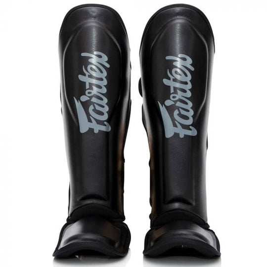 Vooraanzicht van zwarte Booster FXB scheenbeschermers met lichtgrijs Fairtex-logo, geschikt voor kickboksers en intensieve training.