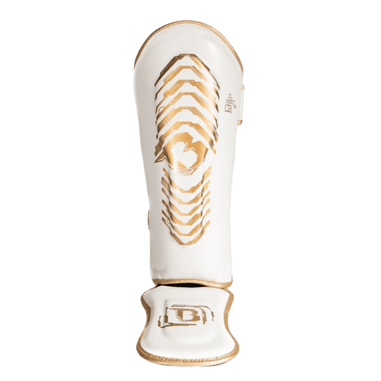 Vooraanzicht van een witte Booster scheenbeschermer met gouden accenten en een solide constructie voor optimale bescherming tijdens het trainen.