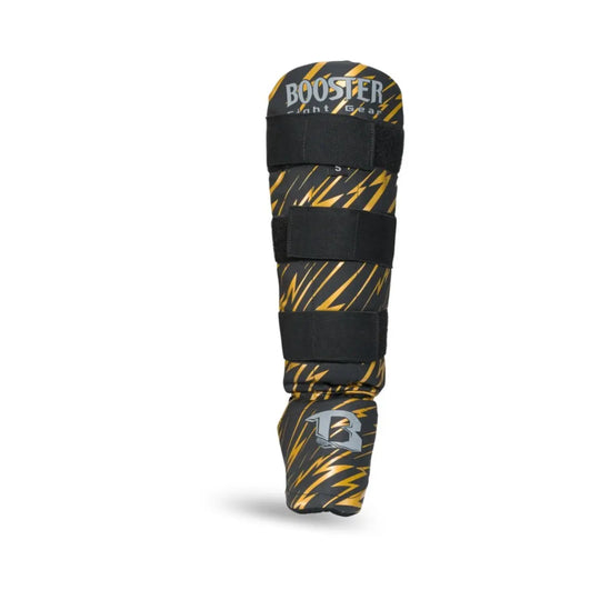 Kickboksscheenbeschermer van Booster in zwart met gouden bliksemprint, zilverkleurig logo op de voet en drie stevige klittenbandsluitingen.










