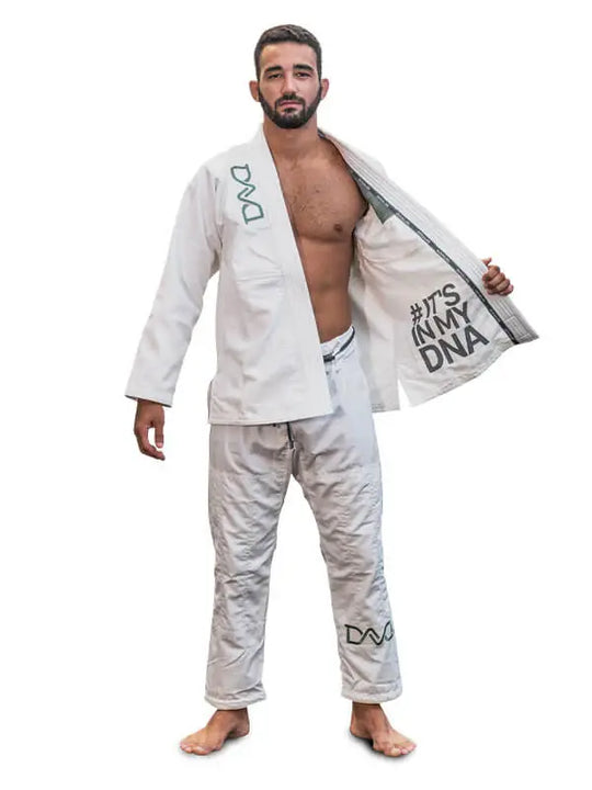 Man in witte BJJ-gi met open jasje waarop de tekst "#IT'S IN MY DNA", poserend op blote voeten.