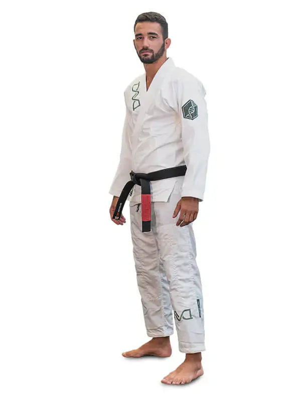 Man in witte BJJ-gi met zwarte band staat rechtop in ontspannen houding op een witte achtergrond.