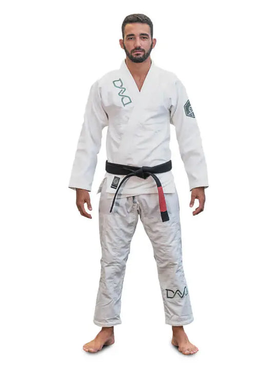 Man in witte BJJ-gi met zwarte band staat rechtop en kijkt recht vooruit op een witte achtergrond.