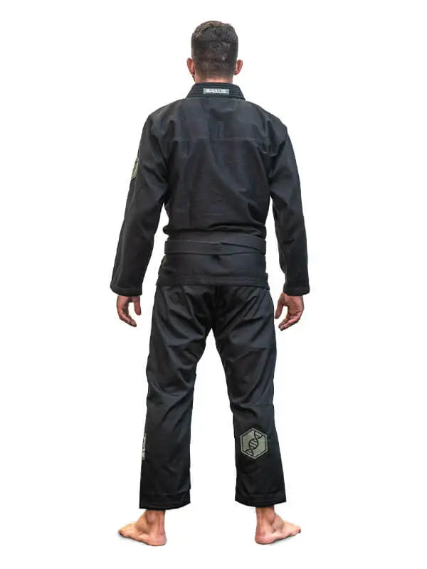 Man in zwarte BJJ-gi met zwarte band, van achteren gefotografeerd, staand op een witte achtergrond.
