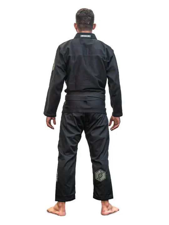 Man in zwarte BJJ-gi met zwarte band, van achteren gefotografeerd, staand op een witte achtergrond.