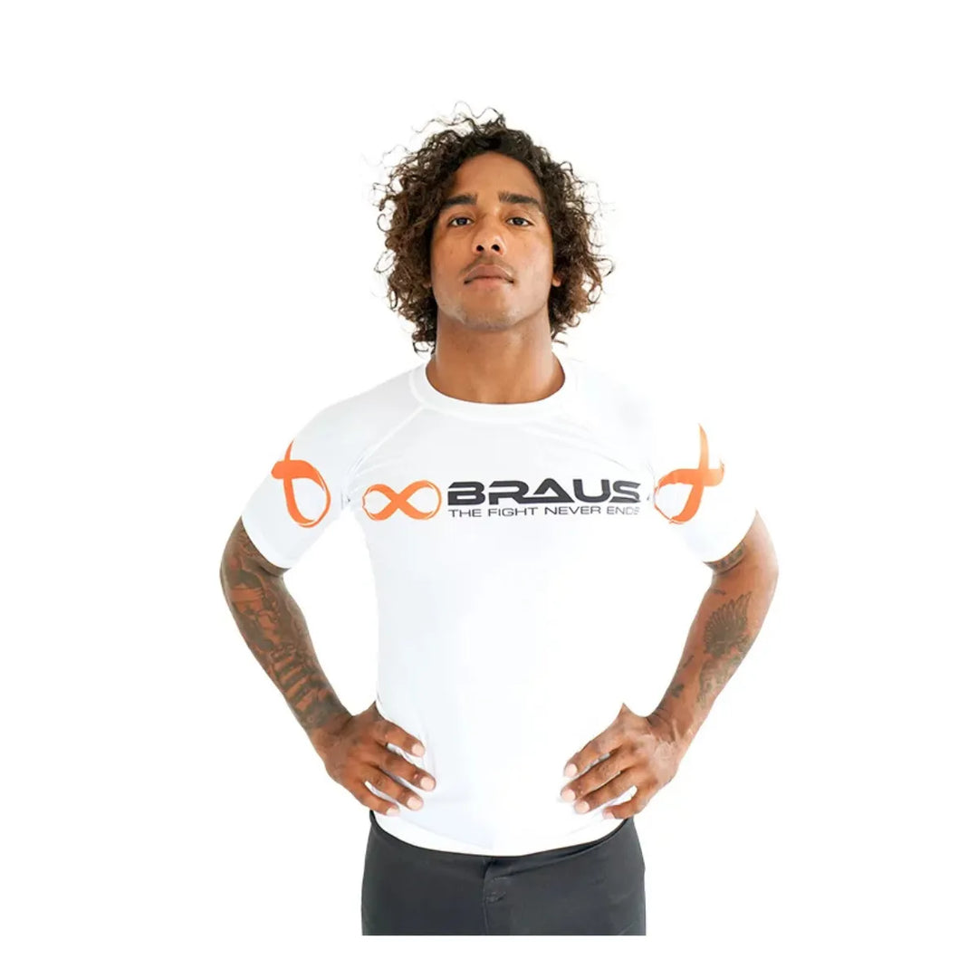 Vooraanzicht van man met witte Braus rashguard met korte mouwen, oranje logo’s en zwarte opdruk, geschikt voor kickboksen en boksen.