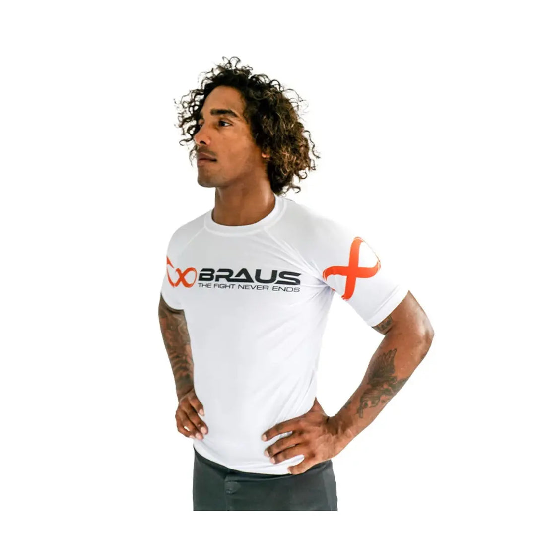 Man draagt witte Braus rashguard met korte mouwen, zwart logo en oranje details, geschikt voor kickboksen en boksen.