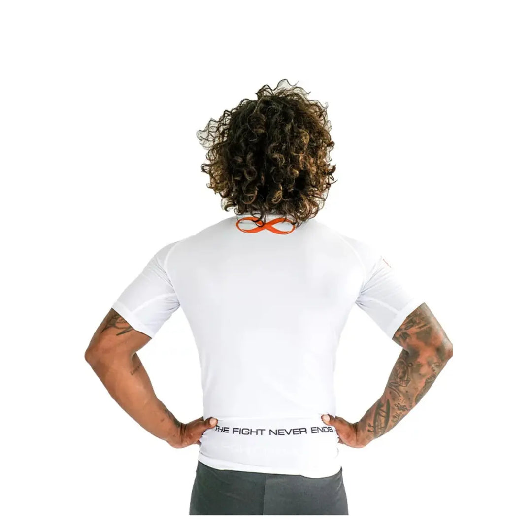 Achteraanzicht van man met witte rashguard met oranje logo en tekst "The Fight Never Ends" op de tailleband.