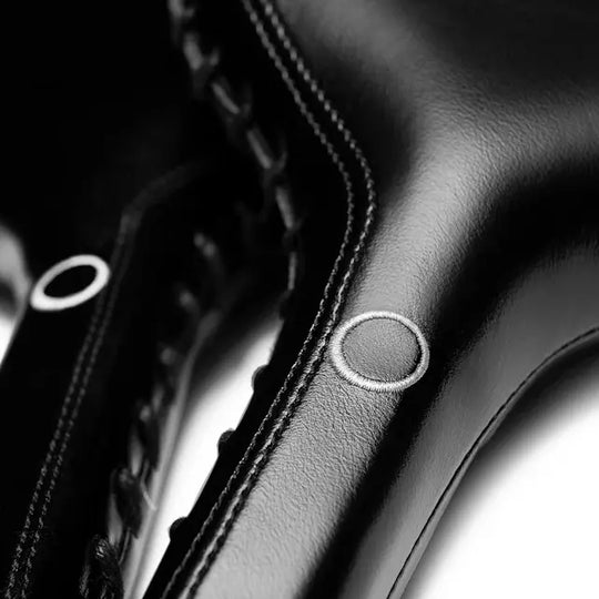 Gedetailleerde close-up van zwart leren bokspad met wit cirkellogo, zichtbare stevige stiksels en glad oppervlak.