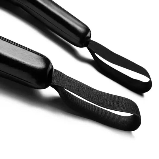 Detailfoto van twee zwarte trainingsticks met glanzende afwerking en stevige elastische handlussen, liggend op een witte ondergrond.