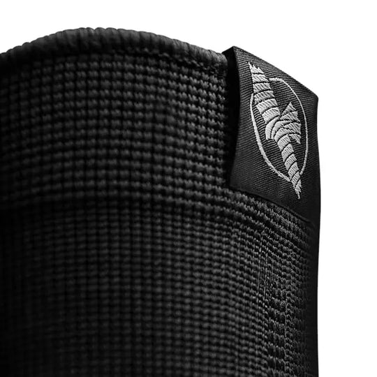 Detailfoto van een zwarte vechtsport bandage met geweven textuur en wit geborduurd Fightstyle-logo op een label.