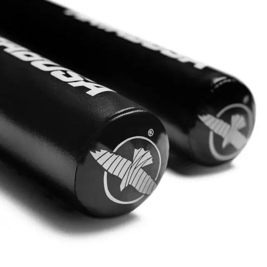 Close-up van het uiteinde van zwarte Hayabusa trainingssticks met wit logo, gefotografeerd op een witte achtergrond.